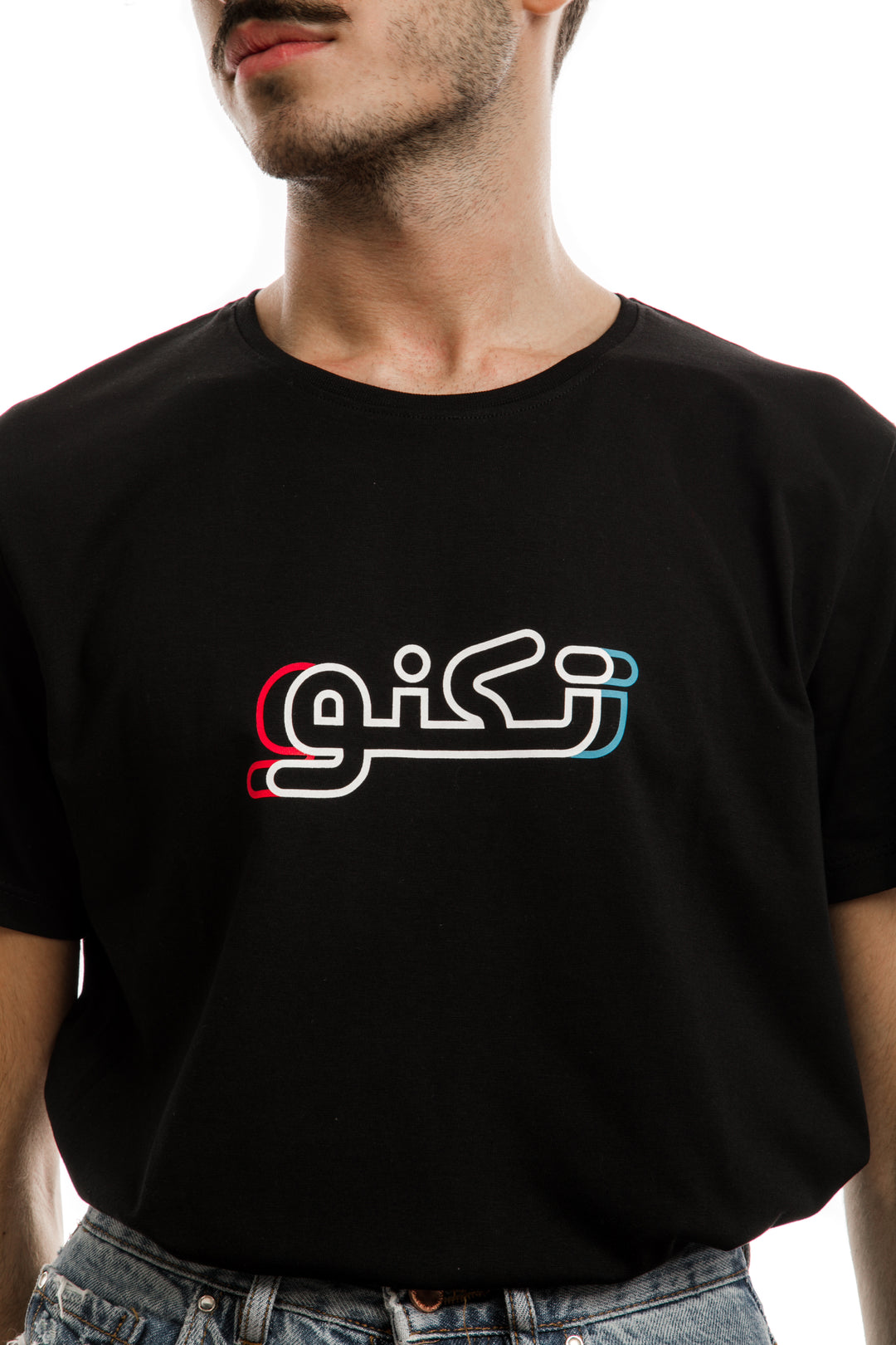 Young adult male wearing black T-shirt with Techno written in Arabic تكنو and printed in blue, red and white silkscreen in the center of the t-shirt.