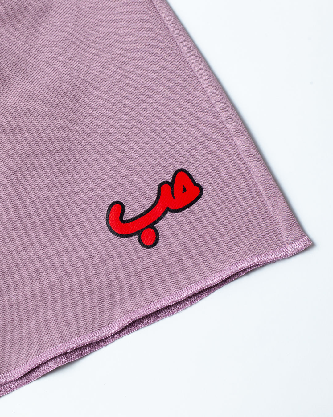 Close up on Hobb written in Arabic حب and printed in red silkscreen on the side of a flared lavender short.