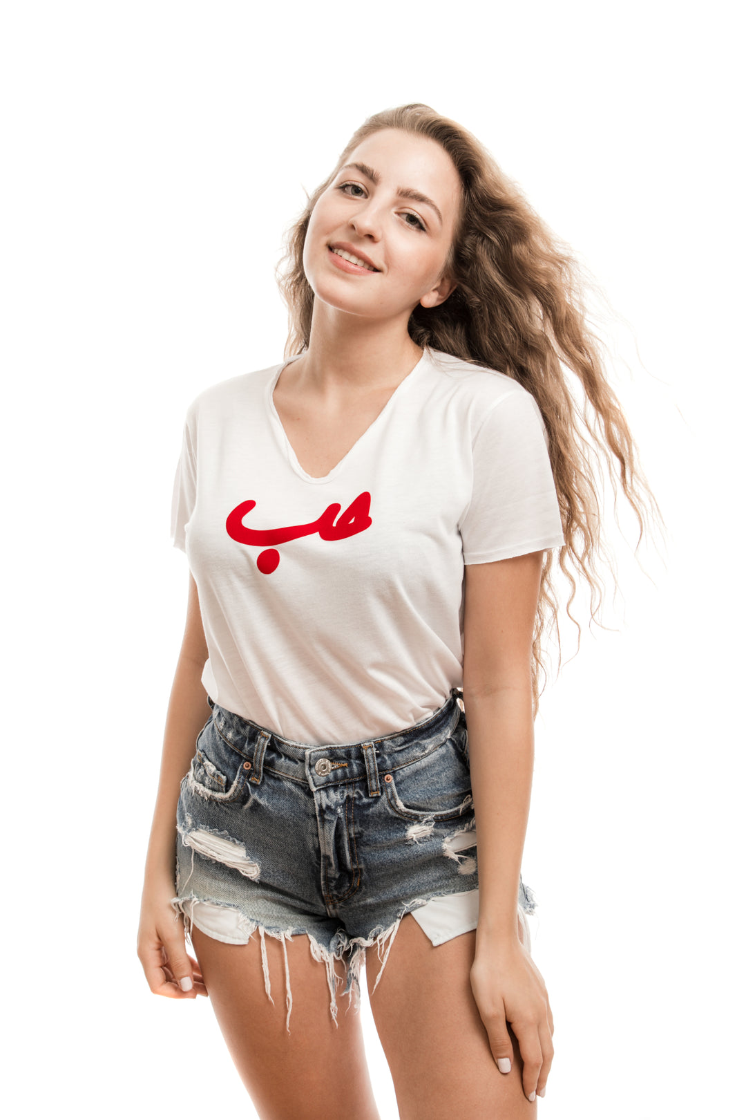 Young adult female wearing white T-shirt with Hobb written in Arabic حب and printed in red velvet in the center of the T-shirt along with blue jeans shorts.