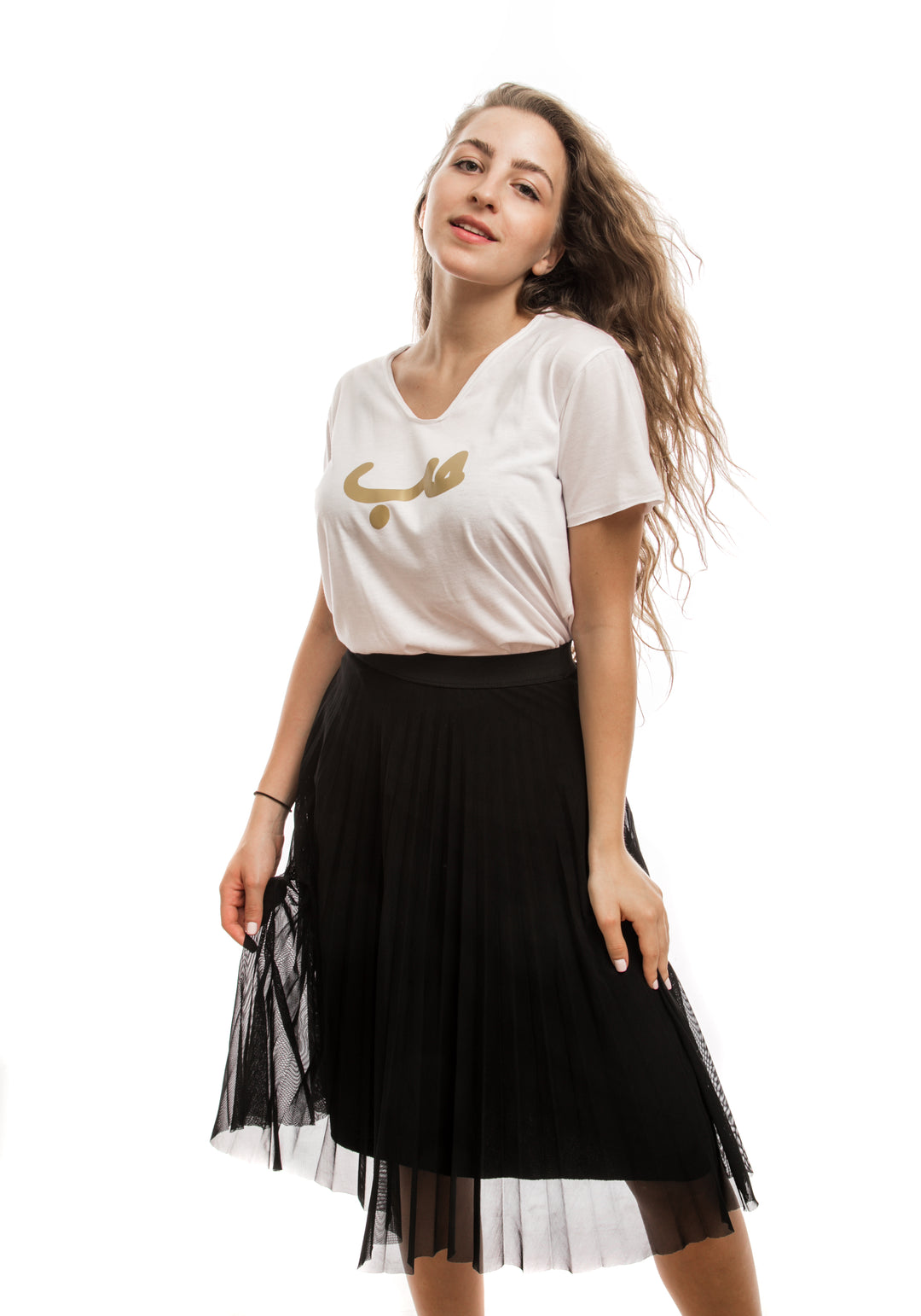 Young adult female wearing white T-shirt with Hobb written in Arabic حب and printed in gold silkscreen in the center of the T-shirt along a black skirt.