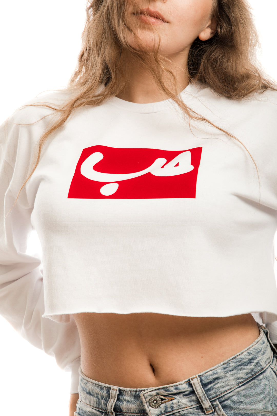 Young adult female wearing white Crop Sweater with Hobb written in Arabic حب in white and printed in a red velvet frame in the center of the Crop Sweater.