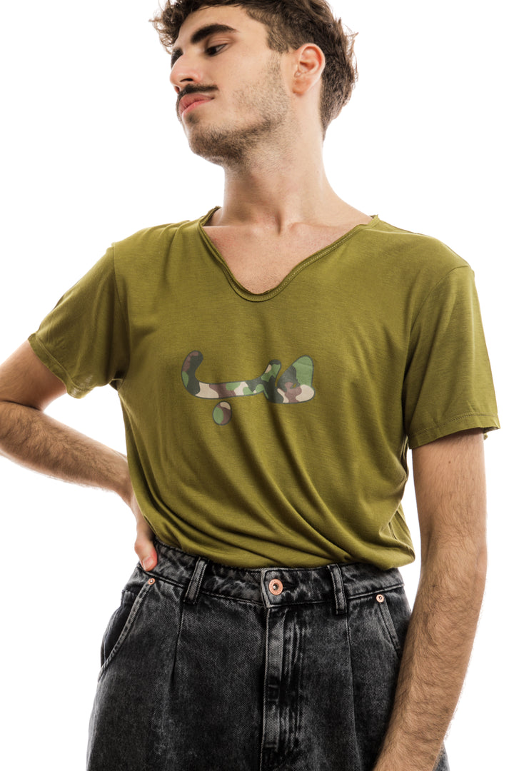 Young adult male wearing olive green T-shirt with Hobb written in Arabic حب and printed in army silkscreen pattern in the center of the T-shirt along with black jeans.
